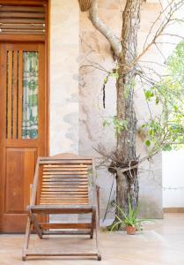 a wooden bench next to a tree next to a door at Nalaka Relaxing Home in Weligama