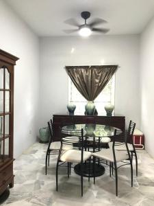 a dining room with a table and chairs and a ceiling fan at The P Lakehouse in Tanjong Sepat