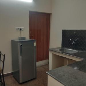 a small kitchen with a sink and a refrigerator at The Briggo Service Aparment in Pondicherry