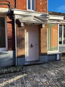 une maison en briques avec une porte blanche sur le côté dans l'établissement Beau studio cosy et meublé Loos lez Lille, France, à Loos