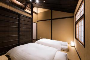 a bedroom with two white beds and a window at Rinn Premium Machiya Koki in Kyoto
