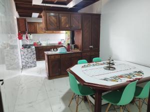 una cocina con mesa y algunas sillas verdes en Casa com Piscina 50000 litros Área Gourmet 3 Suites no Destacado, Bairro mais Nobre de Salinas, en Salinópolis