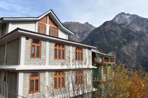 a building with orange windows in front of a mountain at Sonam Homestay Reckong Peo in Kalpa
