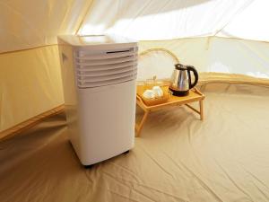 a small refrigerator in a tent with a table at RoomQuest Kid Tung Khao in Ban Huai Sok Noi