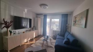 a living room with a blue couch and a large window at STUDIO APARTMAN 404 in Vukovar