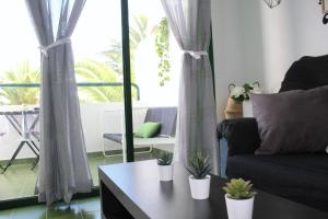 een woonkamer met een bank en een tafel met planten bij Surycan Tropical Garden Apartment in Playa del Inglés
