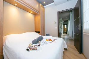 滨海博利厄Appartement Baous 300m de la mer - Happy Rentals的卧室里有一张白色的床，床上放着一本书和一双鞋