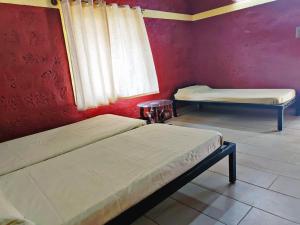 Cette chambre comprend 2 lits et un mur rouge. dans l'établissement STAYMAKER Ruthu Herittage Homes, à Sakleshpur