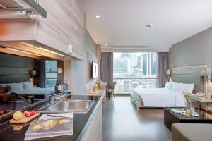 una cocina con fregadero y una cama en una habitación en Adelphi Suites Bangkok - SHA Extra Plus en Bangkok