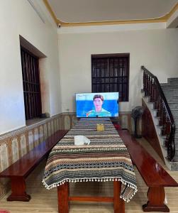 a dining room with a table with a television on it at Homestay Bản Giốc- Tay's Traditional Village in Cao Bằng