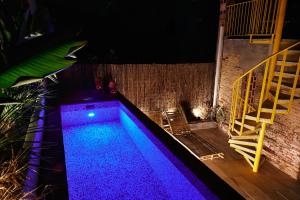 una piscina por la noche con luces moradas en Dormsy aparthotel House, en Arenys de Mar