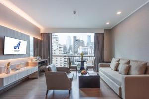 a living room with a couch and a large window at Adelphi Suites Bangkok - SHA Extra Plus in Bangkok