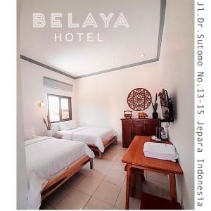 a hotel room with two beds and a table at Belaya Hotel in Jepara