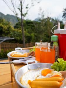 una mesa con dos platos de comida y bebida en RoomQuest Kid Tung Khao, en Ban Huai Sok Noi