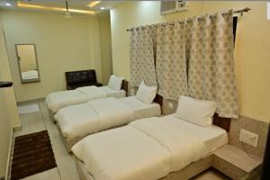 a room with three beds and a mirror at Hotel Raghuveer Inn By BookingCare in Sītāpur Mūāfi