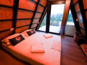a bedroom with a large bed in a room with windows at RoomQuest Kid Tung Khao in Ban Huai Sok Noi