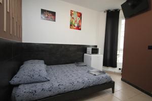 um quarto com uma cama e um micro-ondas na parede em 09 - Chambre proche Paris et Transports avec TV WIFI em Saint-Denis