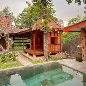 a house with a swimming pool next to a tree at Ndalem Rahadi in Kaliurang