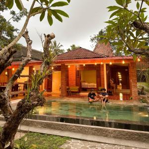 two people sitting in a swimming pool in a house at Ndalem Rahadi in Kaliurang