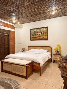 1 dormitorio con 1 cama y una pintura en la pared en Ndalem Rahadi, en Kaliurang
