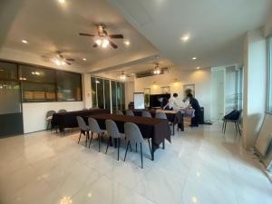 uma sala de jantar com mesas e cadeiras e pessoas a trabalhar em Xanadu Hotel Utapao em Rayong