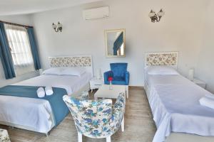 a room with two beds and a chair and a table at Emre Hotel 10Oda in Datca