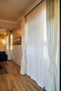 een woonkamer met witte gordijnen en een hardhouten vloer bij Westwood Residences in Arusha