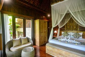 a bedroom with a bed and a couch and a chair at The Banana’s Kumbe Villa in Tampaksiring
