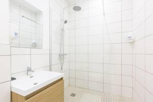 een witte badkamer met een wastafel en een spiegel bij Sereniva - Appartement Familial 2 chambres in Reims