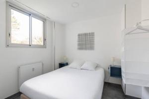 een witte slaapkamer met een wit bed en een raam bij Sereniva - Appartement Familial 2 chambres in Reims