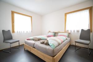 - une chambre avec un lit, 2 chaises et 2 fenêtres dans l'établissement Chasa Bazzell, à Ftan