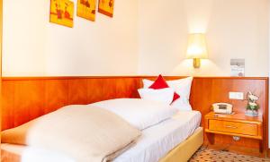 ein Schlafzimmer mit einem Bett mit einem Nachttisch und einer Lampe in der Unterkunft Hotel Friese in Norderney