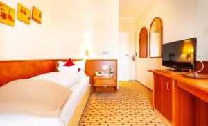 ein Hotelzimmer mit einem Bett und einem Flachbild-TV in der Unterkunft Hotel Friese in Norderney