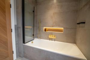 a bathroom with a bath tub with a mirror at Hazelwick Apartment in Crawley