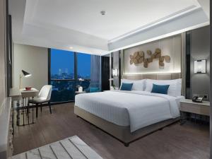 a bedroom with a large white bed and a desk at Royal Malioboro by ASTON in Yogyakarta
