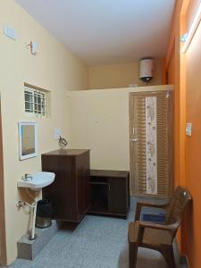 a bathroom with a sink and a toilet and a chair at Royal Comforts in Mysore +5 photos