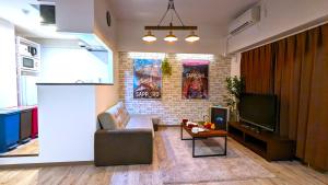 a living room with a couch and a tv at KIYAZA Station Sapporo 2 in Sapporo