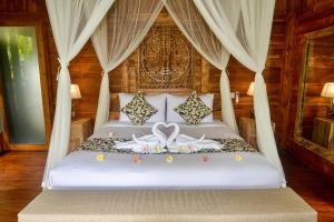 a bedroom with a bed with a white bedspread with a heart shapedvisor at The Banana’s Kumbe Villa in Tampaksiring