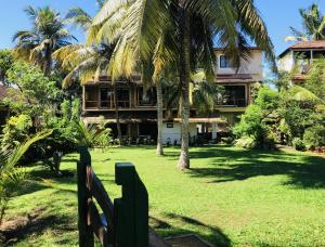 a fence in front of a house with palm trees at Candle House in Kalutara North