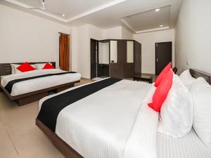 2 łóżka w pokoju hotelowym z czerwonymi poduszkami w obiekcie Club 7 Resort And Banquets w mieście Bareli