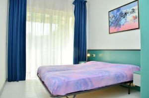 - une chambre avec un lit et une fenêtre avec des rideaux bleus dans l'établissement Colourful seaside flat with pool on the rooftop, à Bibione