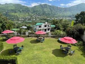 eine Gruppe von Tischen und Stühlen mit roten Sonnenschirmen in der Unterkunft Sangita Resorts in Nainital