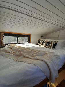 a large white bed in a room with a window at Natura Tiny House in Mărişel