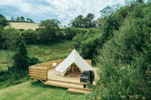a white tent on a wooden deck in a field at Willow Valley Glamping in Bude