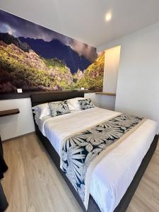a bedroom with a large bed with a painting on the wall at Ononui Lodge Airport, Ocean-View, Private Bathroom and Balcony, Free WiFi and Parking, On-Site Car Rental in Faaa