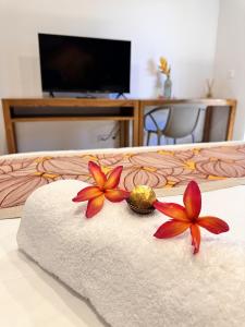 a bed with two flowers on a towel at Ononui Lodge Airport, Ocean-View, Private Bathroom and Balcony, Free WiFi and Parking, On-Site Car Rental in Faaa