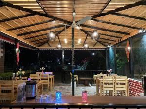 a restaurant with a ceiling fan and wooden tables and chairs at Sangita Resorts in Nainital