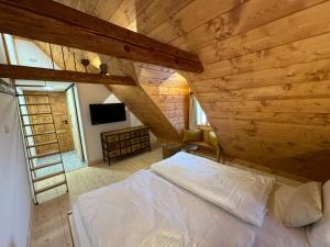 Boutique Cottage Tkalcovna في روكيتنسي ناد جيزيرو: غرفة نوم بسرير ابيض في سقف خشبي