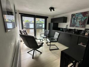 a living room with chairs and a table and a kitchen at Amsterdam-Houseboat-Amstel in Amsterdam