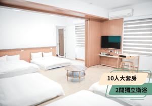 1 dormitorio con 2 camas, escritorio y TV en 西湖柚子家民宿, en Xihu